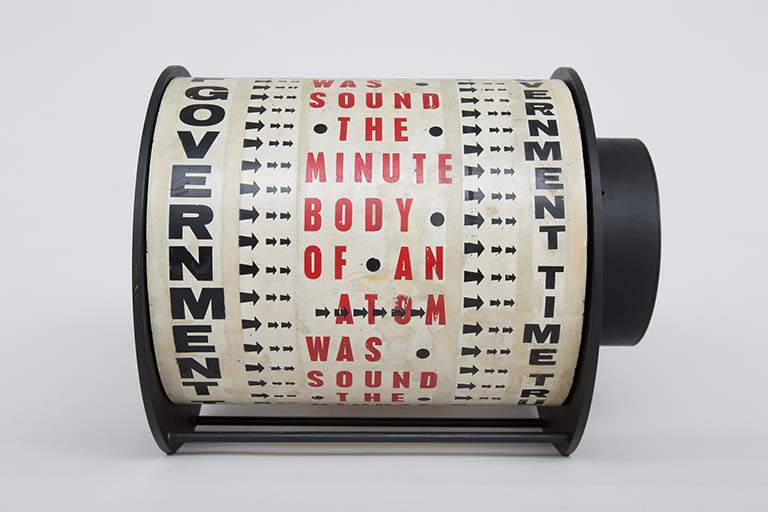 Liliane Lijn. Get Rid of Government Time. 1962. 29.5 x 38 x 30 cm. Letraset on painted metal drum, plastic, painted metal, motor. Words from a poem by Nazli Nour. Frame altered in 1965. Link Here - https://bit.ly/2KcsLpu